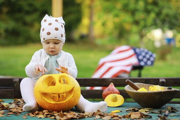 Tradições de outono e preparativos para o feriado de Halloween. Uma casa na natureza, uma lâmpada feita de abóboras está sendo cortada à mesa.