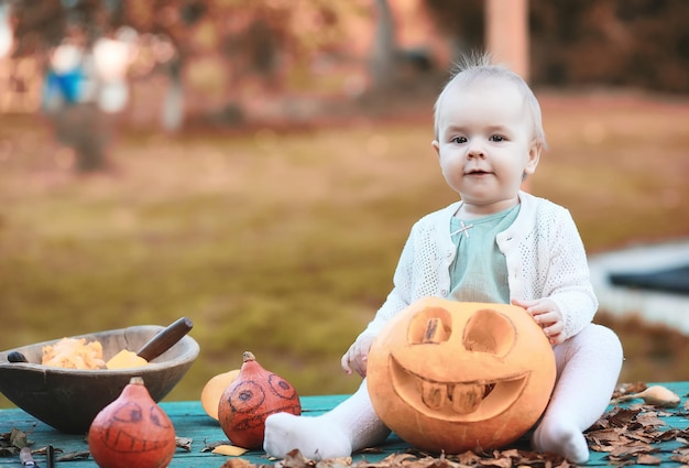 Tradições de outono e preparativos para o feriado de Halloween. Uma casa na natureza, uma lâmpada feita de abóboras está sendo cortada à mesa.