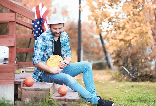 Tradições de outono e preparativos para o feriado Halloween Uma casa na natureza uma lâmpada feita de abóboras está cortando na mesa