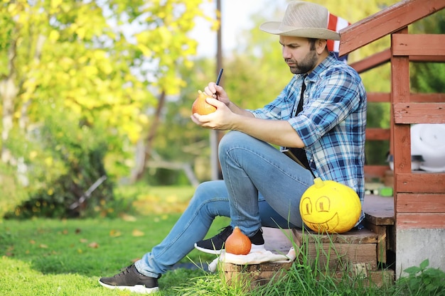 Tradições de outono e preparativos para o feriado Halloween Uma casa na natureza uma lâmpada feita de abóboras está cortando na mesa