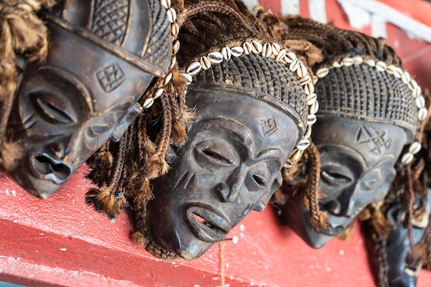 Traditionelle afrikanische Holzmasken hängen zum Verkauf auf dem Straßenmarkt auf der Insel Sansibar Tansania Afrika aus nächster Nähe