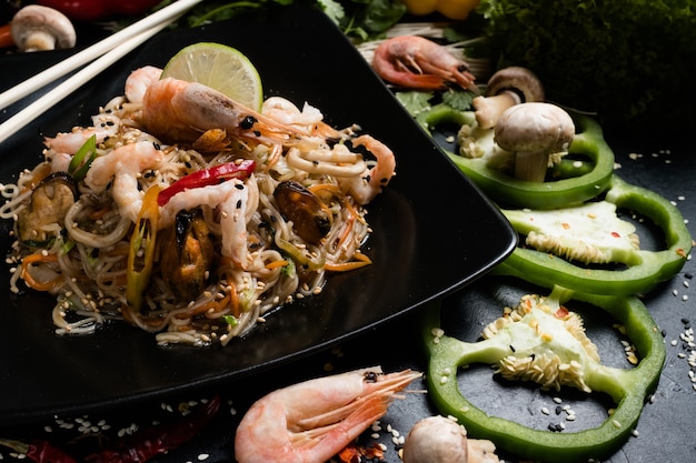 Traditionelle asiatische Küche. Lebensmittelzubereitung Handwerk. Nudeln Garnelen Garnelen Meeresfrüchte und Gemüse auf einem Teller.