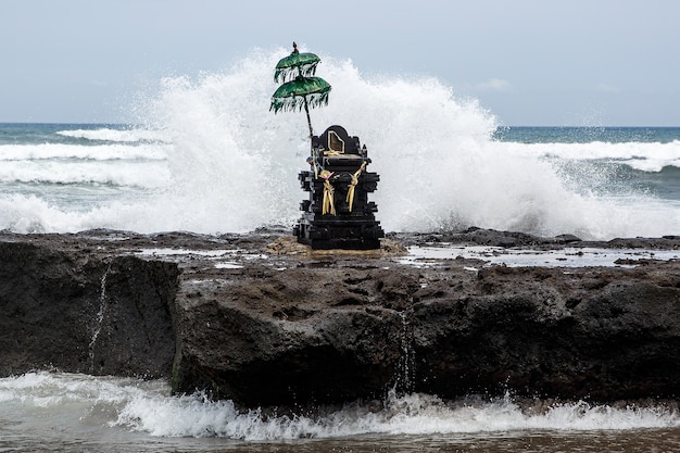 Traditionelle balinesische Skulptur mit hinduistischem Regenschirm und aromatischen Stöcken am Meer.