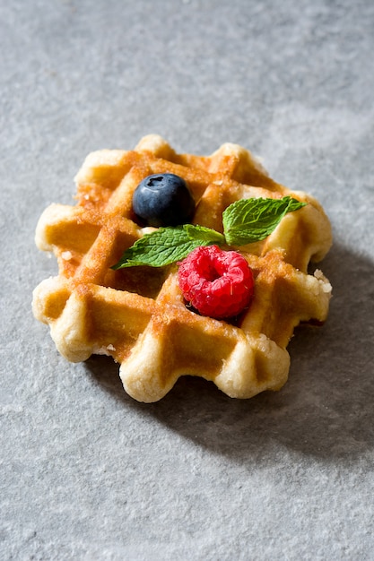 Traditionelle belgische Waffeln mit Blaubeeren und Himbeeren auf grauem Stein