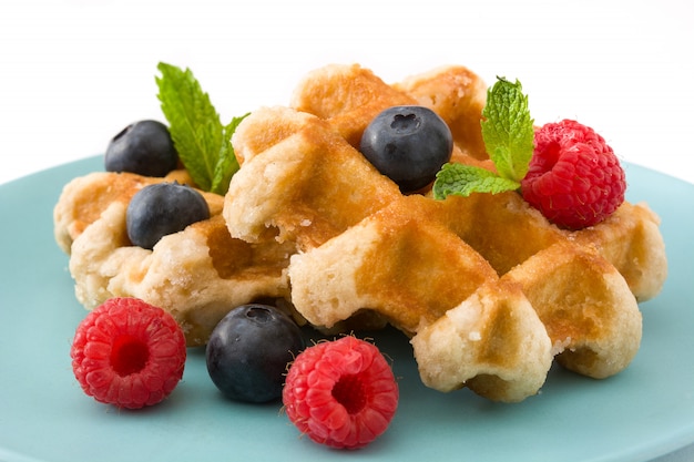 Traditionelle belgische Waffeln mit Blaubeeren und Himbeeren lokalisiert auf Weiß.