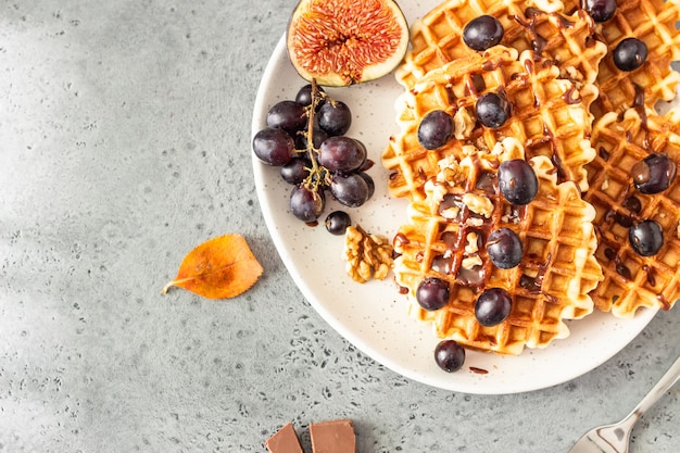 Traditionelle belgische Waffeln mit Karamellsauce, Trauben und Feigen. Gemütliches Herbst- oder Winterfrühstück.