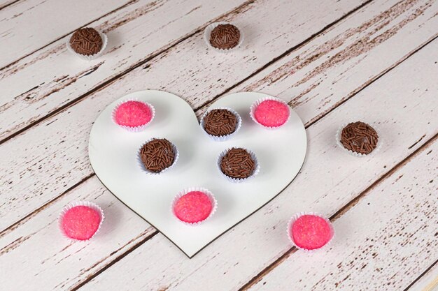 Traditionelle Brigadeiros und Bichos de Pe auf einem herzförmigen Teller. Brasilianische Süßigkeiten.