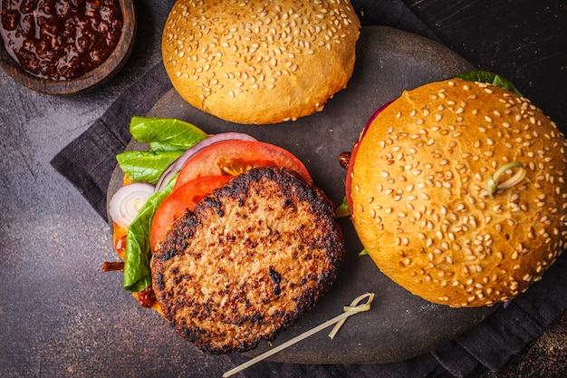 Traditionelle Burger mit Fleisch, Soße und Gemüse auf dunklem Hintergrund, Draufsicht.