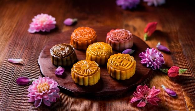 Traditionelle chinesische Mondkuchen Holztisch und Blumen Foto für das Restaurantmenü