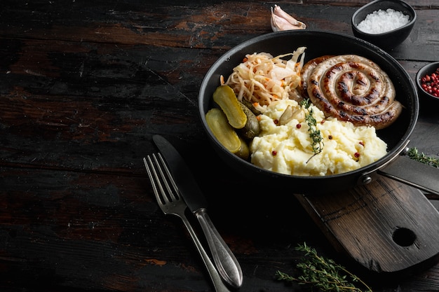 Traditionelle deutsche Würstchen mit Kartoffelpüree und Sauerkraut in einer gusseisernen Pfanne