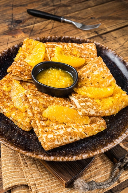 Traditionelle französische Crêpe Suzette mit Orangensauce auf einem Teller Holzhintergrund Draufsicht