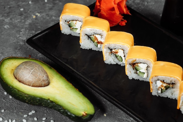 Traditionelle frische japanische sushi-rollen auf einem schwarzen stein teka kaji roll zutaten käse cheder philadelphia-käse gurke thunfisch chips nori-reis