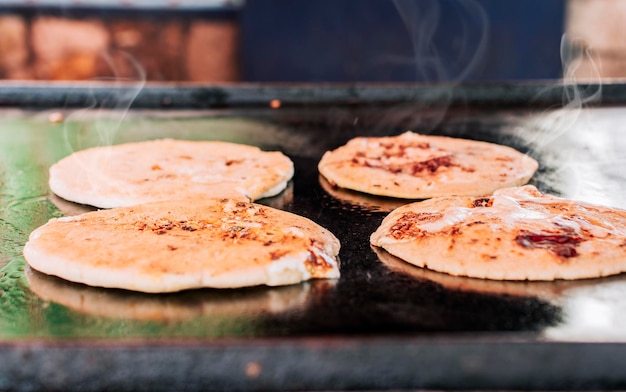 Traditionelle gegrillte Käsepuppen Nahaufnahme von vier traditionellen handgemachten Puppen auf dem Grill Traditionelle nicaraguanische Puppen mit geschmolzenem Käse auf einem Grill