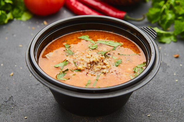 Traditionelle georgische Suppe Kharcho mit Fleisch und Reis auf dunklem Steinhintergrund