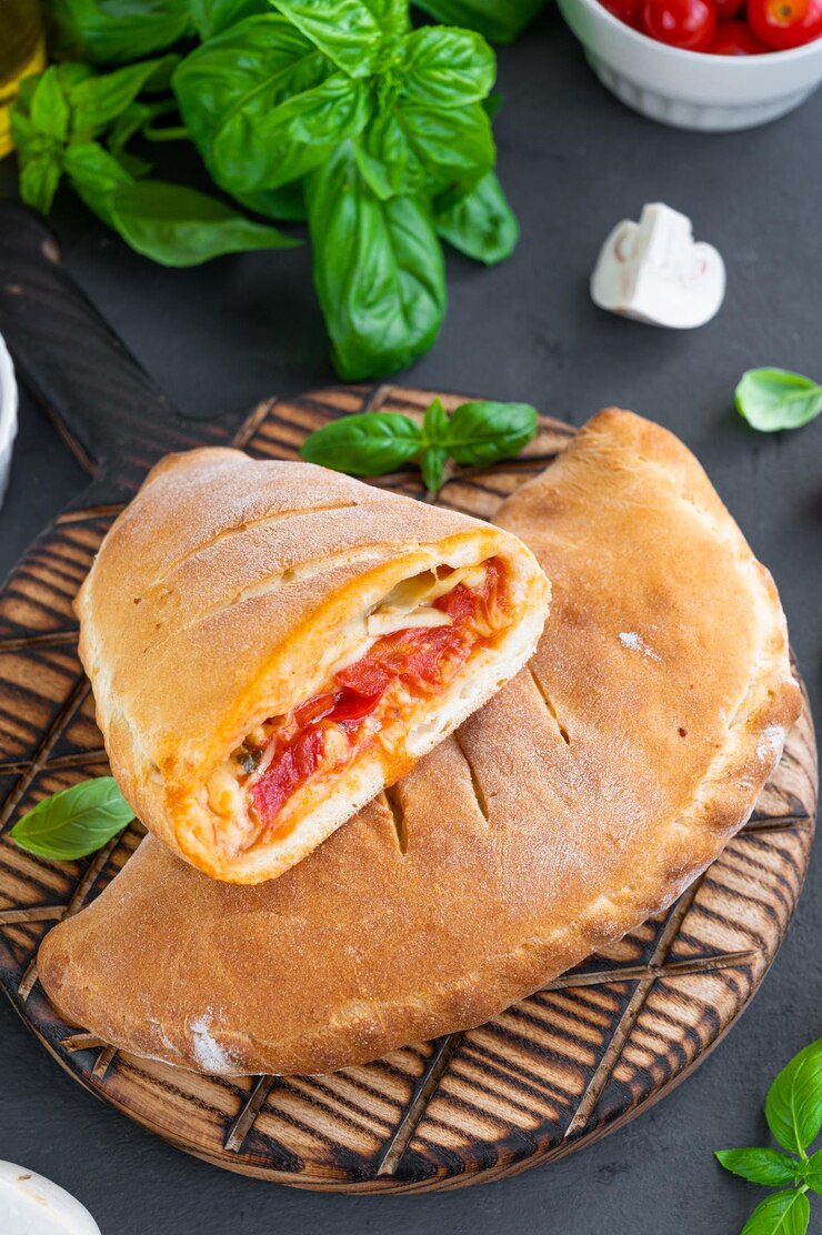 Traditionelle geschlossene italienische Calzone-Pizza mit Tomatensoße, Mozzarella-Käse und Pilzen