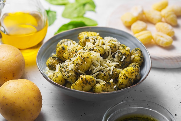Traditionelle Gnocchi mit Pesto-Sauce auf grauem Betonhintergrund. Es wurde mit Kartoffel- und Weizenmehlteig zubereitet. Gnocchi sind Knödel, meist oval