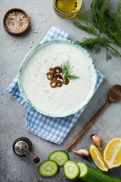 Traditionelle griechische Sauce Tzatziki. Joghurt, Gurke, Dill, Knoblauch und Salzöl in einer Keramikschale auf einem grauen Stein oder Betonhintergrund