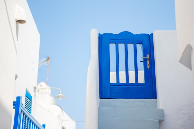 Traditionelle Häuser mit blauer Tür und weißer Treppe in den schmalen Straßen von Mykonos, Griechenland.