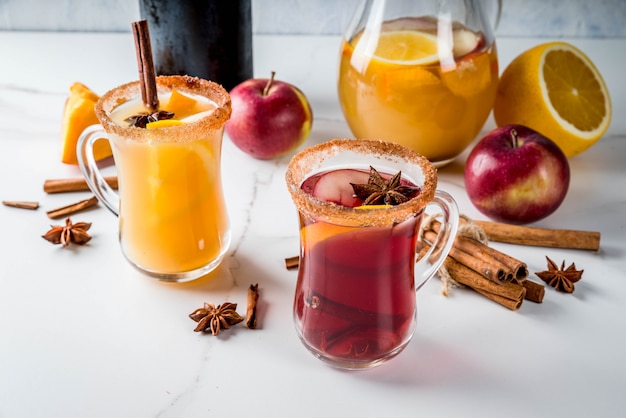 Traditionelle Herbst- und Wintergetränke und Cocktails. Heiße würzige Sangria des weißen und roten Herbstes mit Anis, Zimt, Apfel, Orange, Wein. In Glasbechern weißer Marmortisch. Tiefenschärfe textfreiraum