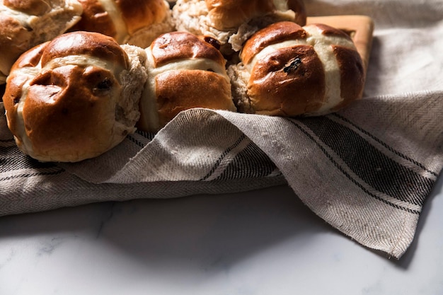 Traditionelle Hot Cross Buns mit Rosinen auf einem Holzbrett