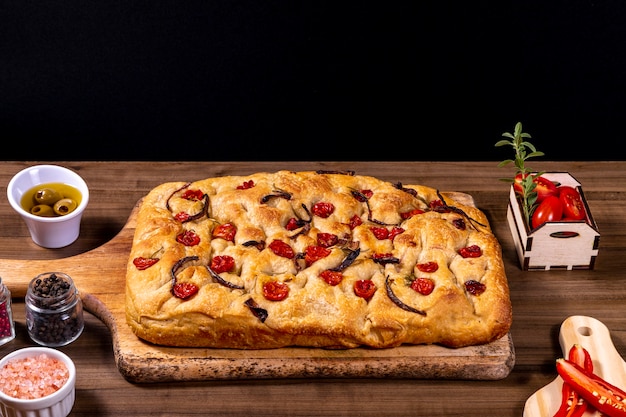 Traditionelle italienische Focaccia mit Kirschtomaten, schwarzen Oliven und Rosmarin.