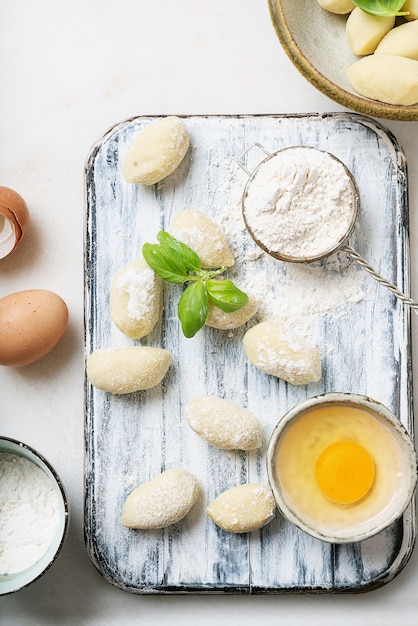 Traditionelle italienische Kartoffel-Gnocci, verziert mit Basilikumblatt, Eiern, Mehl. Draufsicht. Flache Lage