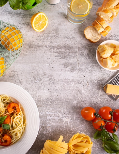 Traditionelle italienische Pasta mit Meeresfrüchten und Garnelen auf weißem Teller mit Tomaten-Basilikum-Parmesan-Käse und anderen Zutaten zum Kochen Leckeres und köstliches Essen Draufsicht Kopierbereich