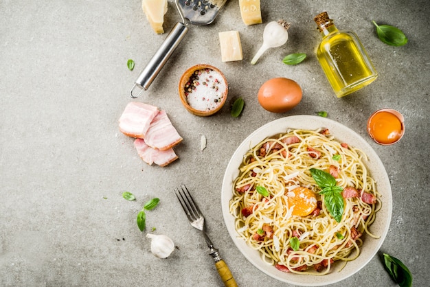 Traditionelle italienische pasta, spaghetti carbonara mit speck, sahnesauce, parmesankäseparmesan, eigelb und frischem basilikum