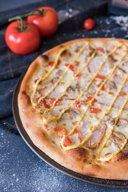 Traditionelle italienische Pizza mit chiken, Schinken auf dunkelblauer Steintabelle