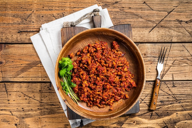 Traditionelle italienische Tomatensauce Bolognese mit Hackfleisch in einer Holzplatte mit Kräutern Holzhintergrund Ansicht von oben