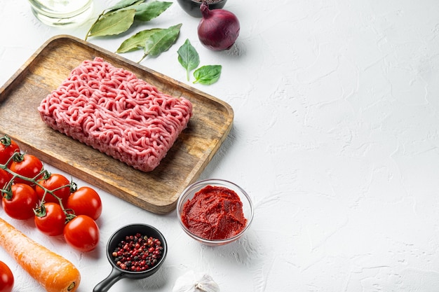 Traditionelle italienische Tomatensauce Bolognese mit Zutaten, Hackfleisch-Tomaten und Kräutern, auf Holztablett, auf weißem Stein