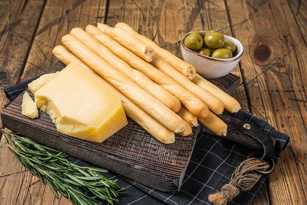 Traditionelle italienische Vorspeise Grissini-Brotstangen auf Holzbrett mit Oliven und Parmesan-Käse Hölzerner Bakground Draufsicht