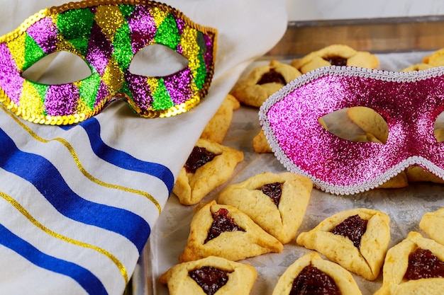 Traditionelle jüdische Hamantaschen-Kekse mit Marmelade, Tallit und Maske für Purim