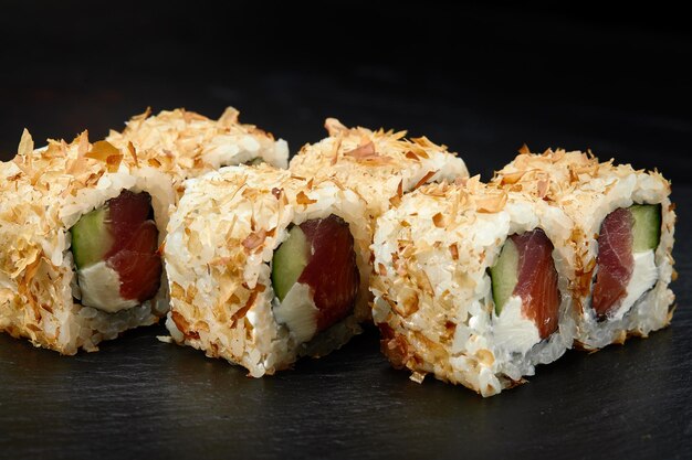 Traditionelle köstliche frische Sushi-Rolle auf schwarzem Hintergrund Sushi-Rolle mit Reis Frischkäse Avocado Lachs Sesam Philadelphia Sushi-Menü Japanische Küche Restaurant