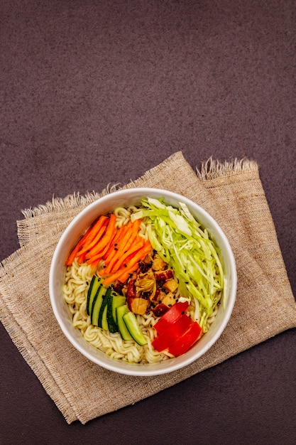 Traditionelle koreanische Nudelschale mit geräuchertem Hähnchen, frisch geschnittenem Gemüse und Sesam