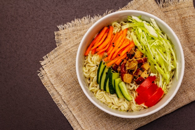 Traditionelle koreanische Nudelschale mit geräuchertem Hähnchen, frisch geschnittenem Gemüse und Sesam