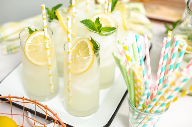 Traditionelle Limonade mit einer Scheibe frischer Zitrone und Minze mit Papierstroh im Glas.