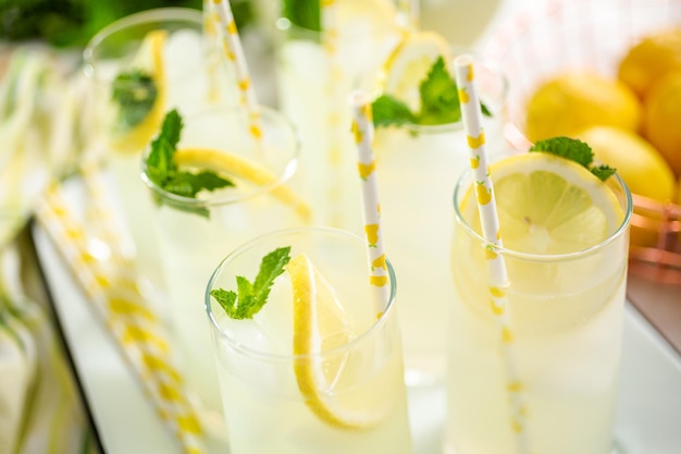 Traditionelle Limonade mit einer Scheibe frischer Zitrone und Minze mit Papierstroh im Glas.