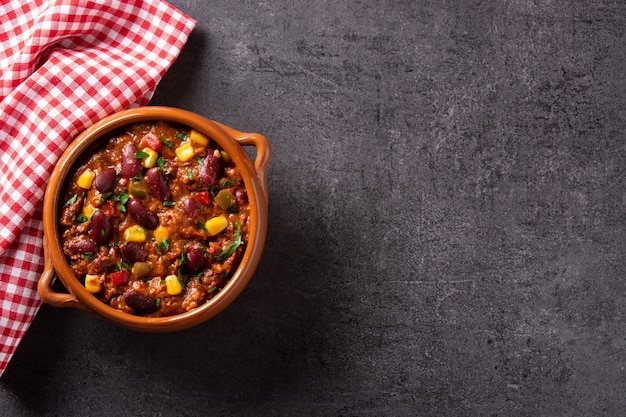 Traditionelle mexikanische Tex-Mex-Chili con Carne in einer Schüssel auf schwarzem Hintergrund.