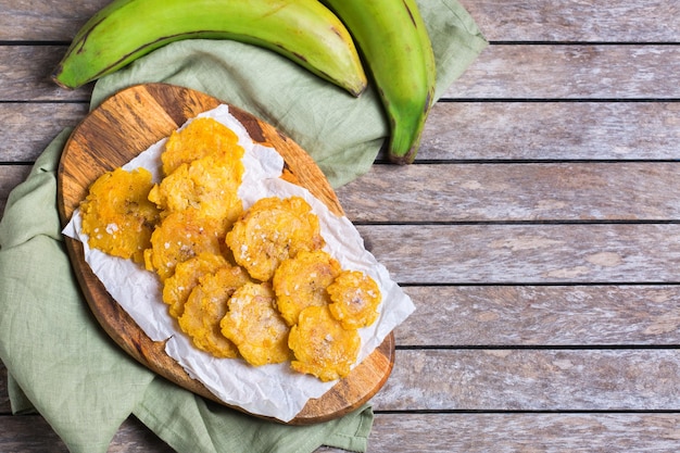 Foto traditionelle mittelamerikanische karibische kubanische kolumbianische küche. gebratene tostones, grüne bananenbananen mit guacamole-sauce. ansicht von oben, flach liegend