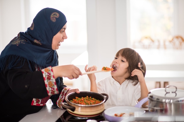 Traditionelle muslimische Frau mit nettem Kind im Haus