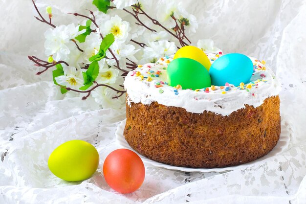 Traditionelle Osterleckereien: Kuchen und bunte Ostereier auf einer weißen Spitzentischdecke