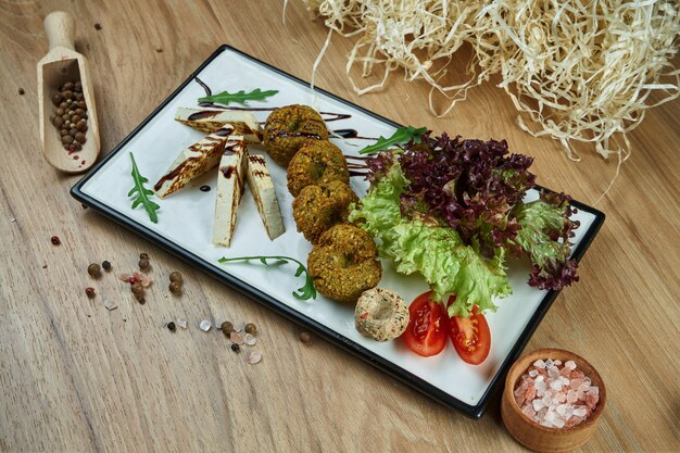 Traditionelle Ostküche Gericht Falafel mit Hummus und gebratenem Tofu-Käse mit Salatgarnitur auf einem weißen Teller. Essen flach lag. Vegetarisches Essen