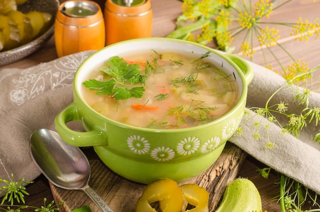 Traditionelle Rassolnik-Suppe mit eingelegten Gurken in einer grünen Terrine auf Holzhintergrund