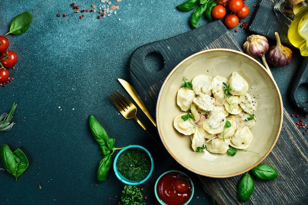 Traditionelle Ravioli mit Fleisch Pelmeni auf einem Teller mit Butter und Zwiebeln Auf einem Teller Restaurant serviert Close Up Auf einem dunklen Stein-Hintergrund