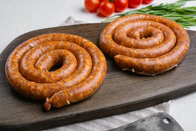 Traditionelle rohe Spiralwurst aus Schweinefleisch auf grauem Betontischhintergrund