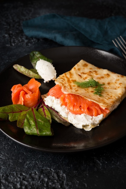 Traditionelle russische dünne Pfannkuchen mit Füllung, rotem Fisch und Frischkäse, Nahaufnahme