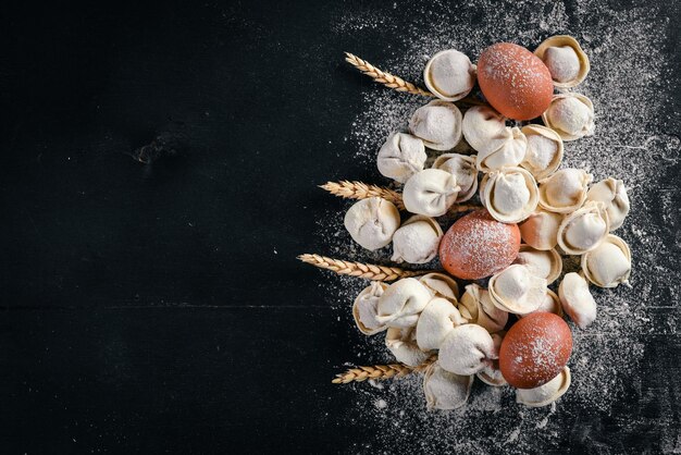 Traditionelle russische Pelmeni-Ravioli-Knödel mit Fleisch auf schwarzem Betonhintergrund Draufsicht Copyspace