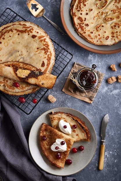 Traditionelle selbst gemachte Pfannkuchen mit Moosbeeren dienten auf grauer Steintabelle. Ansicht von oben.