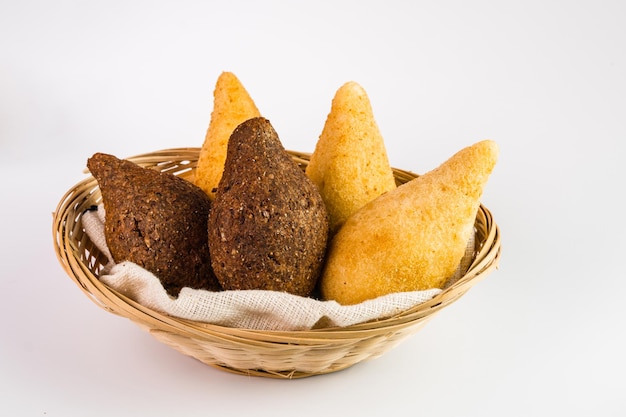 Traditionelle Snacks Chicken Coxinha, bekannt als Coxinha in Brasilien und Fried Kibe serviert in einem Korb Weißer Hintergrund Selektiver Fokus